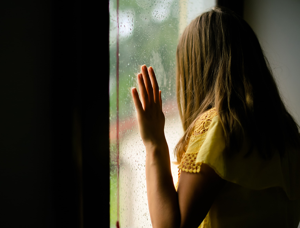 Eine Frau steht an einem Fenster und blickt raus