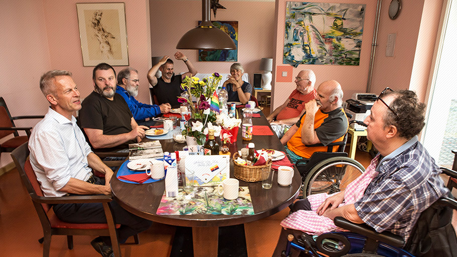 LSBTI*-Themenwoche: Acht Männer aus der Pflege-WG Lebensort Vielfalt in Berlin sitzen an einem Frühstückstisch